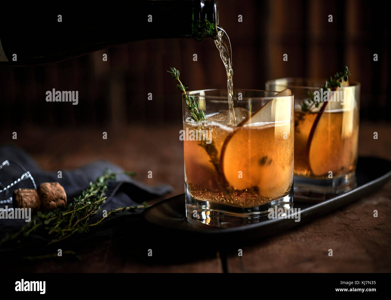 Whiskey cocktail with fresh thyme and pear on a rustic wood background