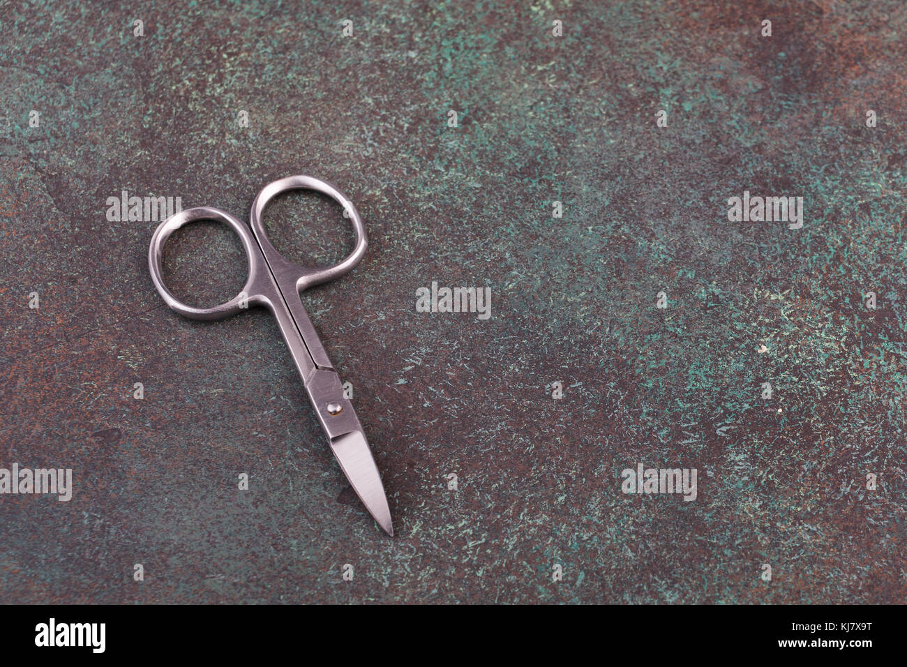 manicure scissors on a textured dark background Stock Photo