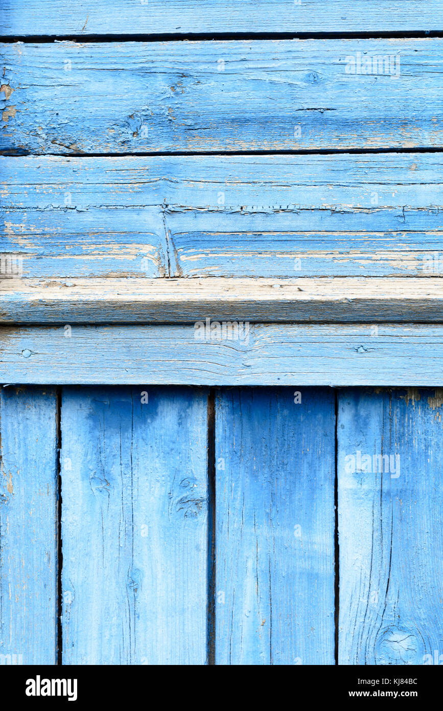 Vintage old wooden slats or boards with coats of bright blue peeling and flaking into a pattern of paint flecks Stock Photo