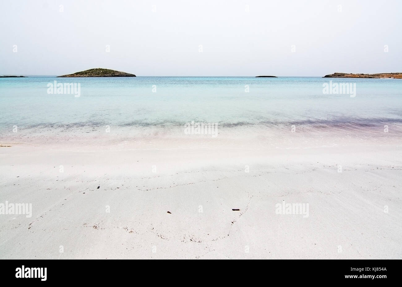 Empty dreamy soft paradise beach with crystal clear water on an overcast day in October in Illetas, Formentera, Balearic islands, Spain. Stock Photo