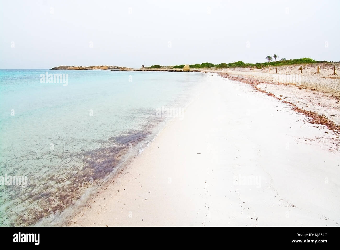 Empty dreamy soft paradise beach with crystal clear water on an overcast day in October in Illetas, Formentera, Balearic islands, Spain. Stock Photo