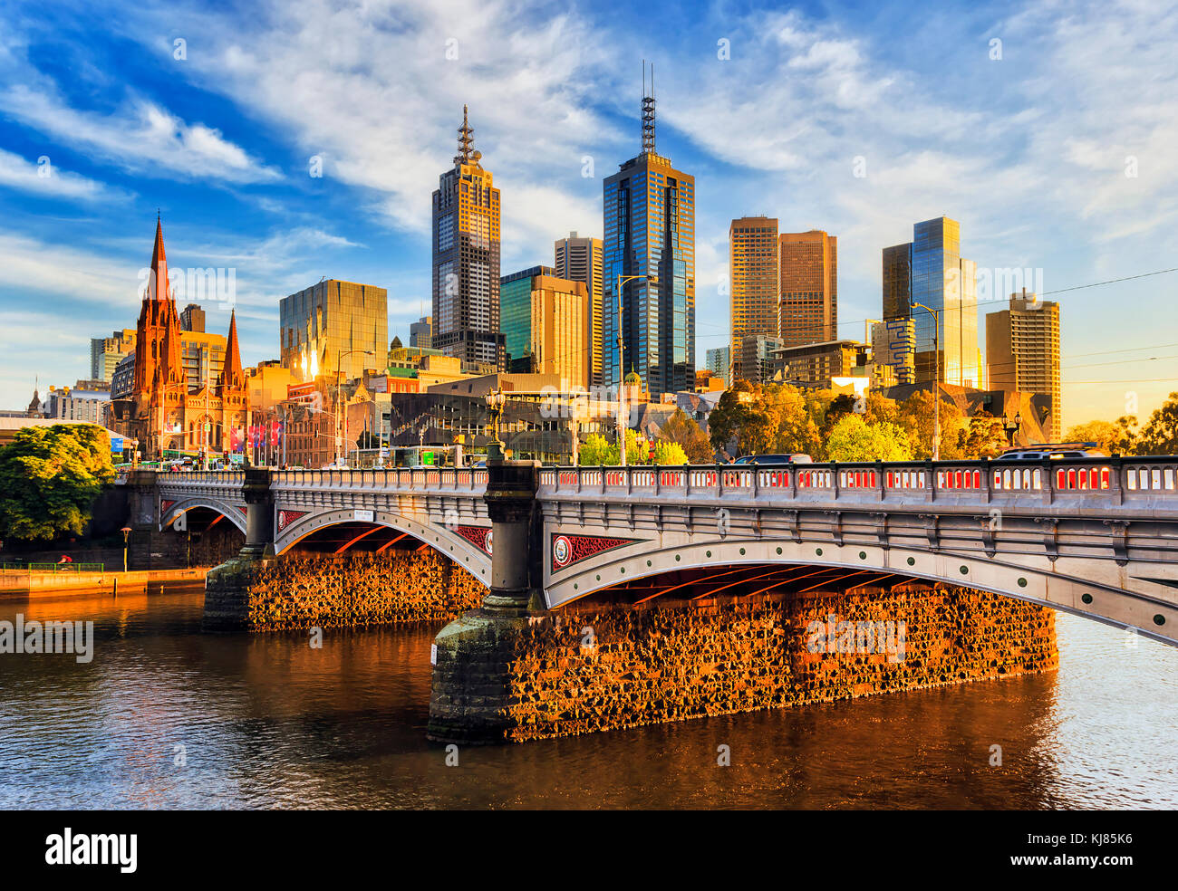 Warm morning light on high-rise towers in Melbourne CBD above Princes bridge across Yarra river. Stock Photo