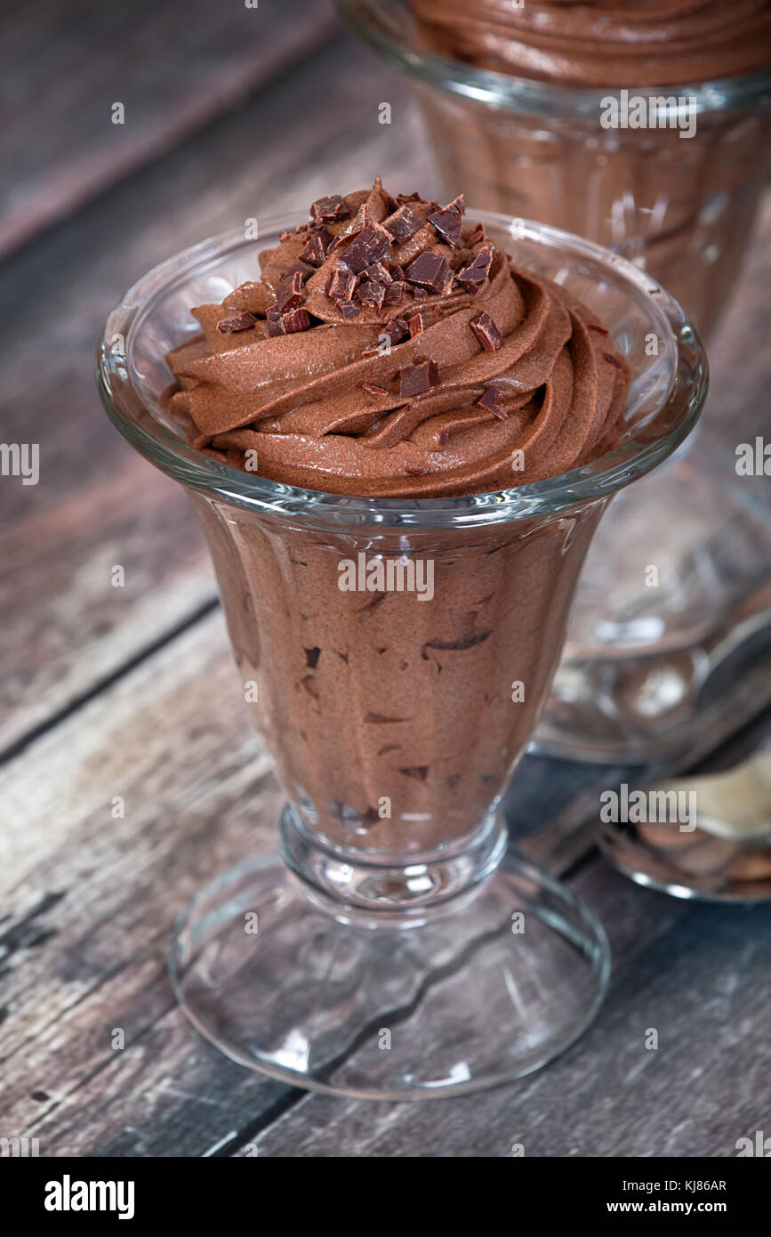 Dark chocolate mousse dessert served in glass bowl. Rustic wooden table ...