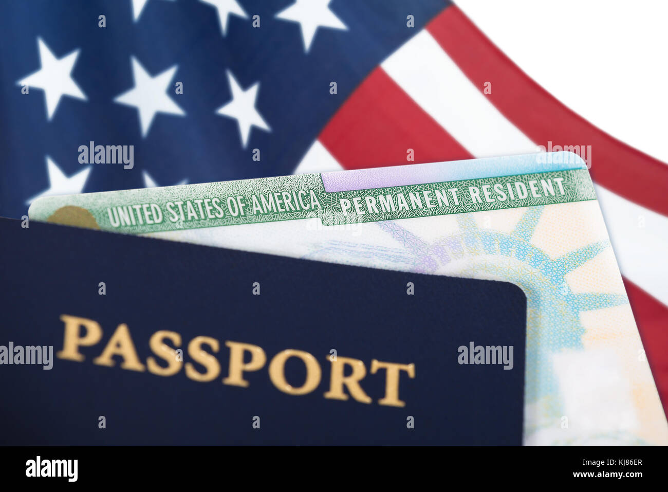 United States of America permanent resident card, green card, displayed with a US flag in the background and a passport in the foreground. Immigration Stock Photo