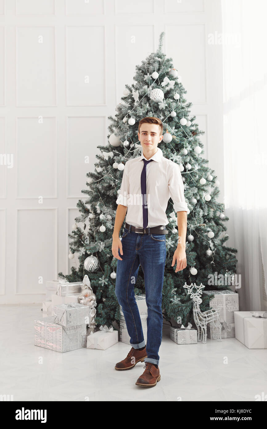 Guy teen meets Christmas. He is dressed in a white shirt, tie and jeans.  Teenage Fashion Stock Photo - Alamy