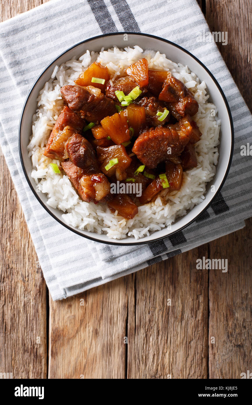 Filipino belly pork hamonado with pineapple and rice close-up in a bowl. Vertical top view from above Stock Photo