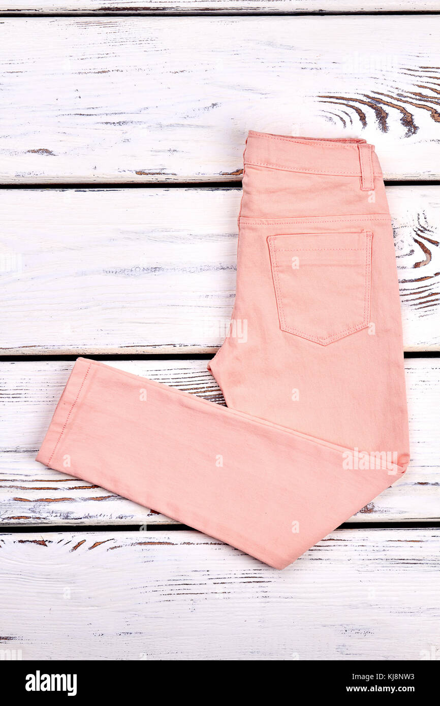 Måned Hong Kong Tage en risiko Girls new folded colored jeans. Solid peach color summer trousers for young  women on old wooden background. Female denim clothes on sale Stock Photo -  Alamy