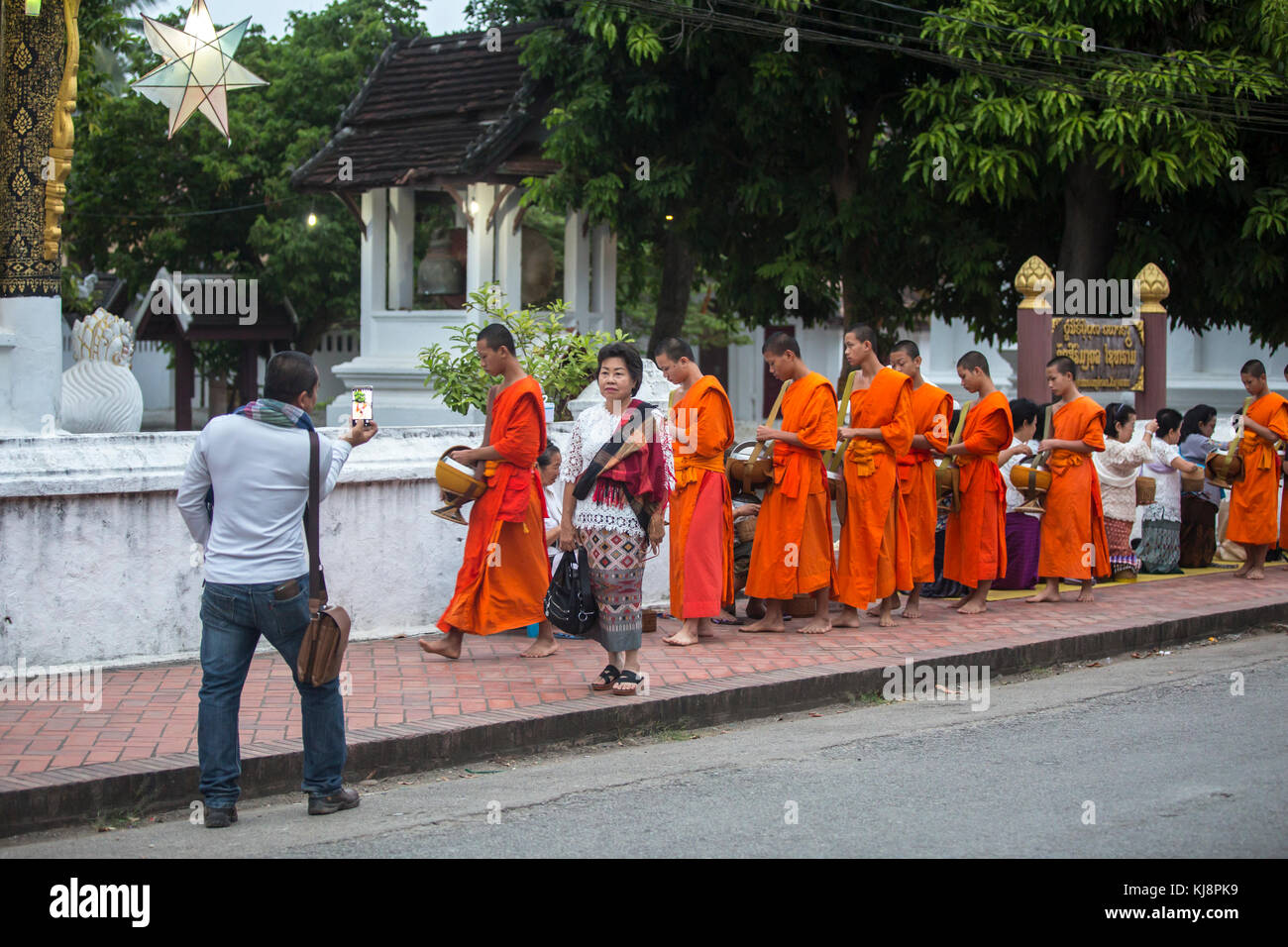 Luang Prabang, Laos - November 19, 2017: Torists taking photos of buddhist monks on everyday morning traditional alms giving in Luang Prabang, Laos. Stock Photo