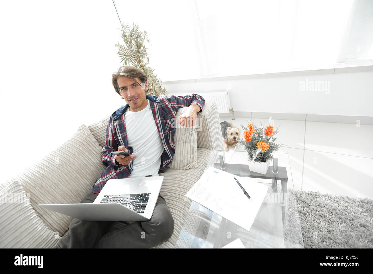 successful guy with laptop and smartphone sitting on sofa in living
