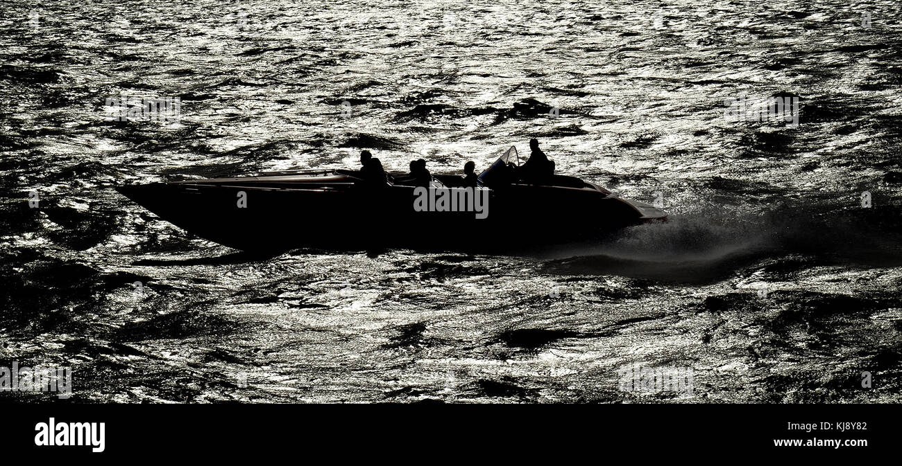 Pleasure trip speedboat in silhouette at speed. Stock Photo
