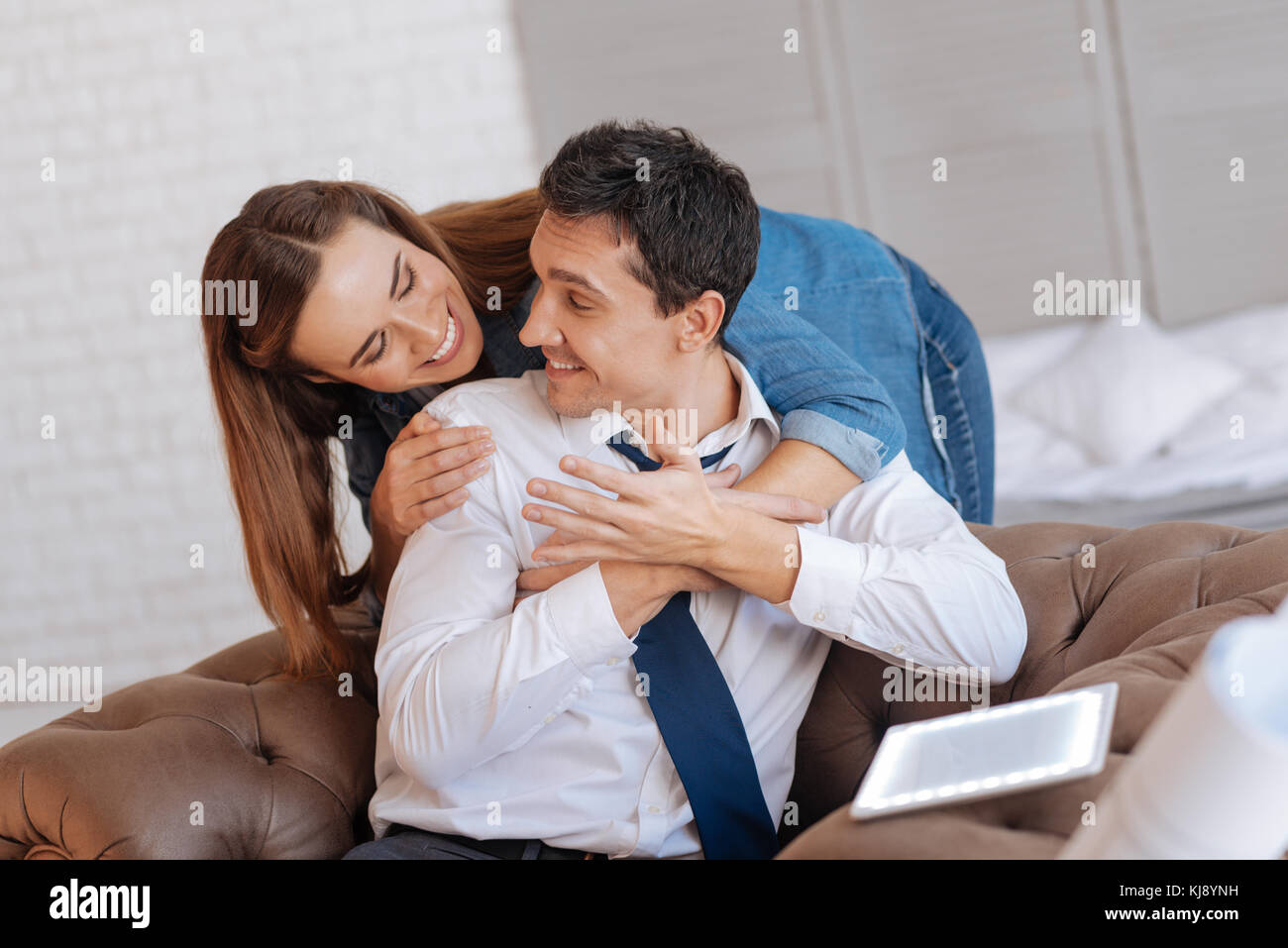 Loving wife smiling to her kind husband while hugging him Stock Photo