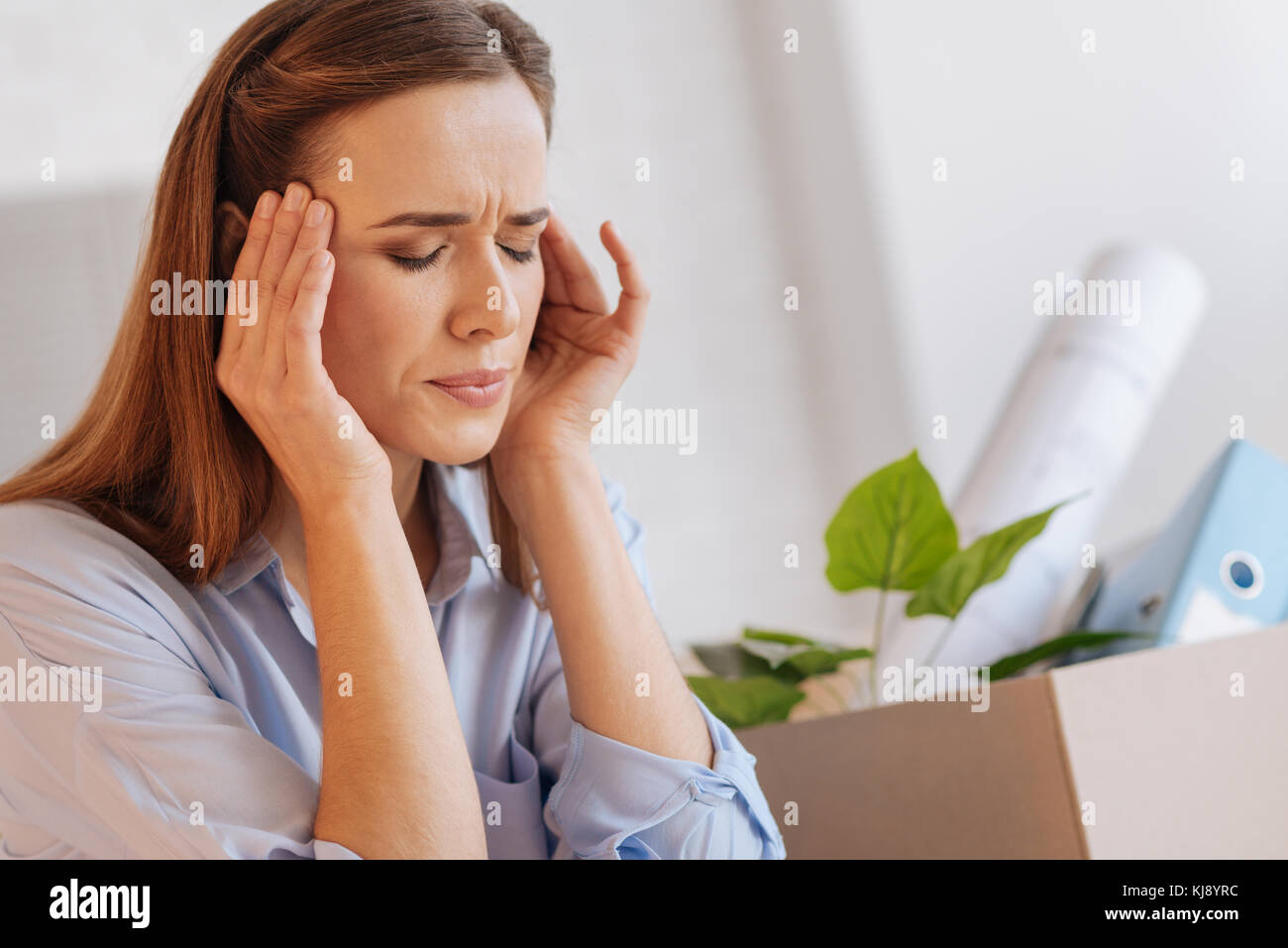 Nervous emotional woman having a headache after being dismissed Stock Photo
