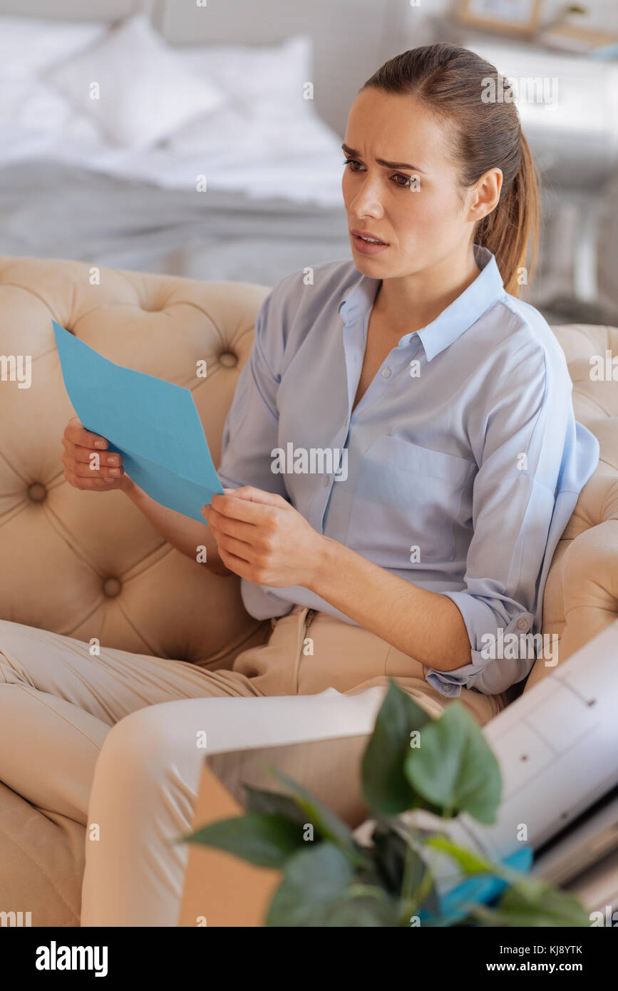 Unhappy disappointed woman reading an unpleasant document from work Stock Photo