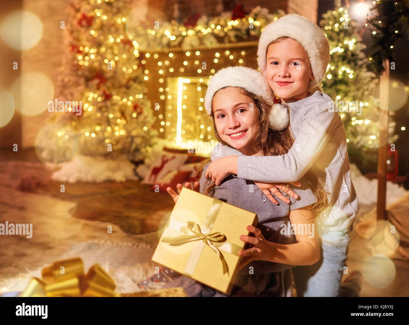 Two children with gifts in a room on Christmas. Stock Photo