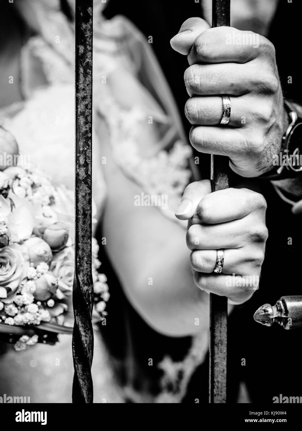 A newly-married couple puts their hands on an iron bar showing their wedding rings. Stock Photo