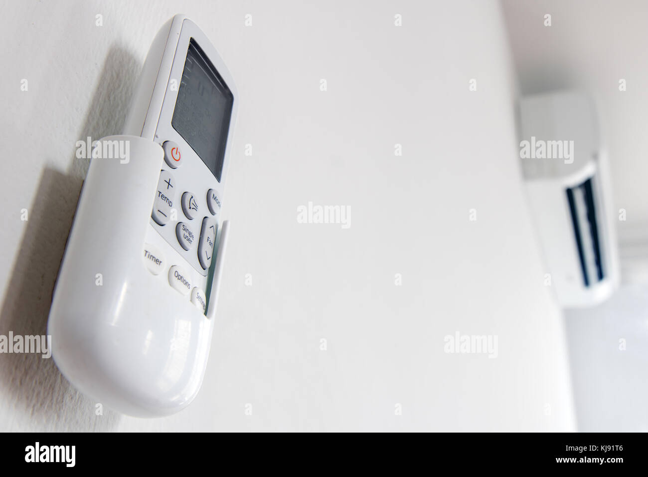 Remote control close up with air conditioner hang on white wall. Air conditioner inside the room