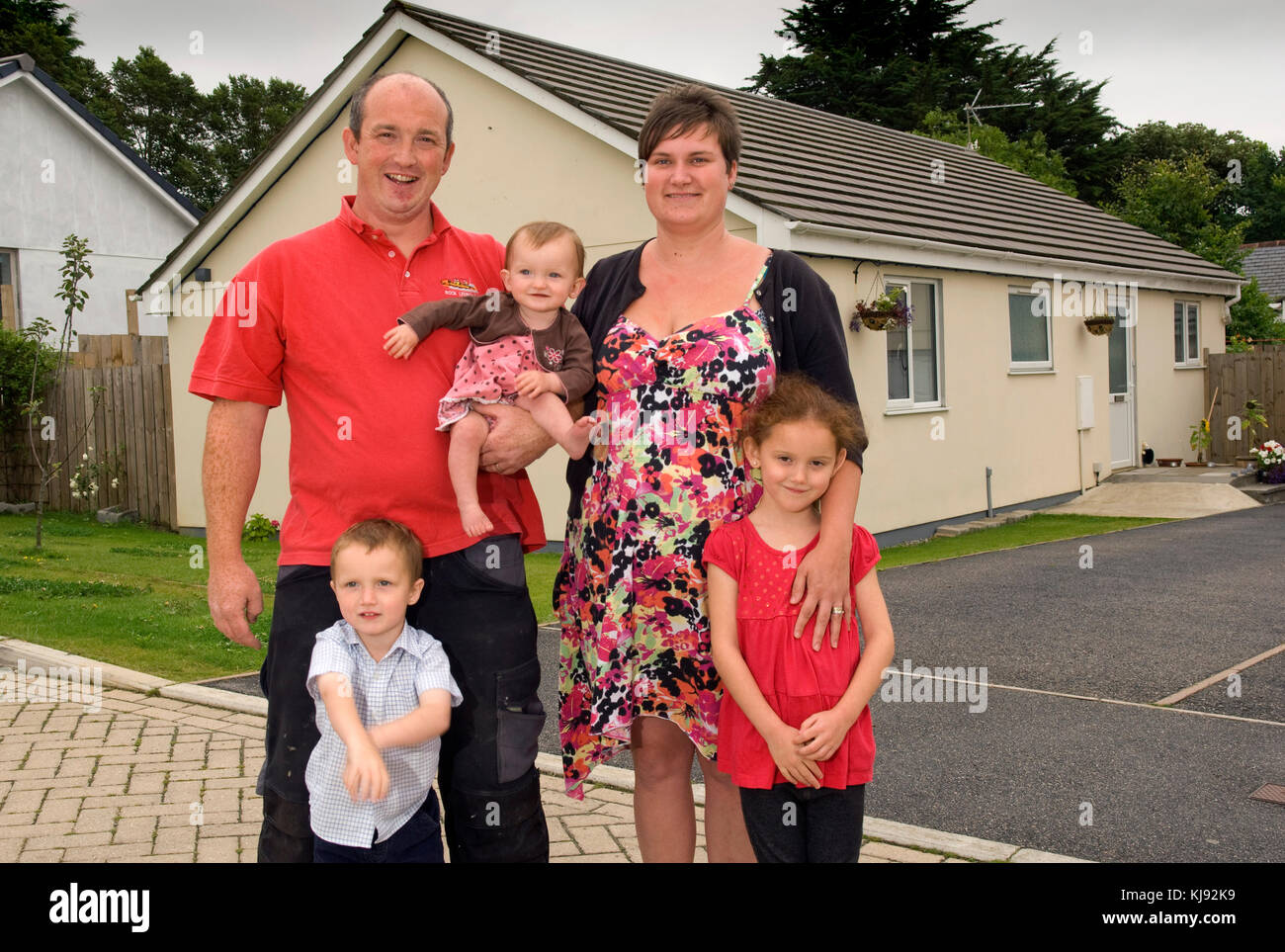 Family standing front of their home Stock Photo - Alamy