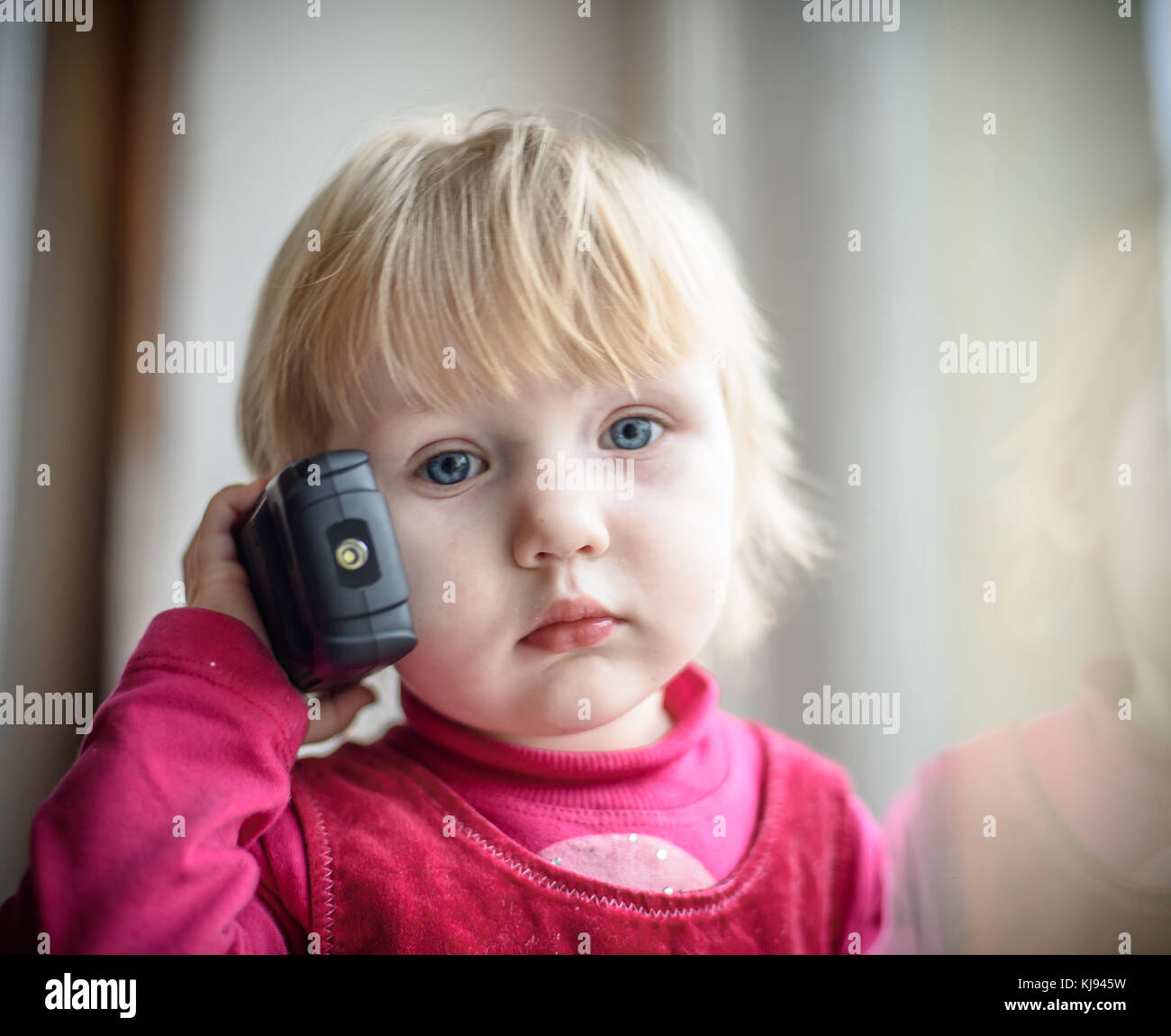 little girl in a red dress talking on the phone Stock Photo