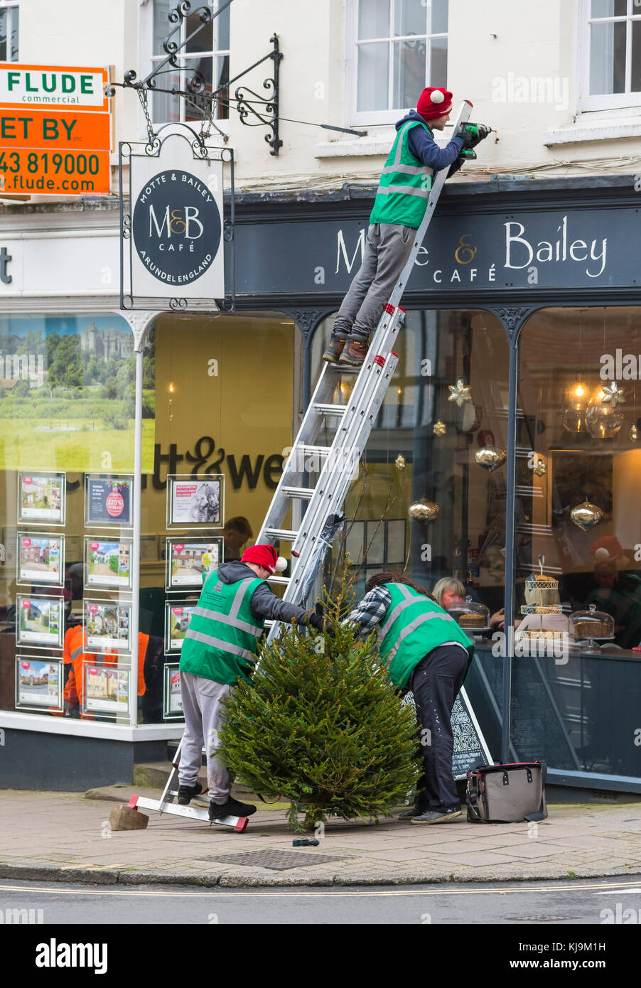 People dressed with Christmas hats putting up a Christmas tree in Arundel, West Sussex, England, UK. Stock Photo