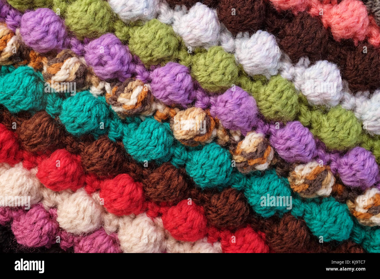 Multi-coloured crochet bobble stitches in diagonal stripes, soft yarn abstract background texture Stock Photo