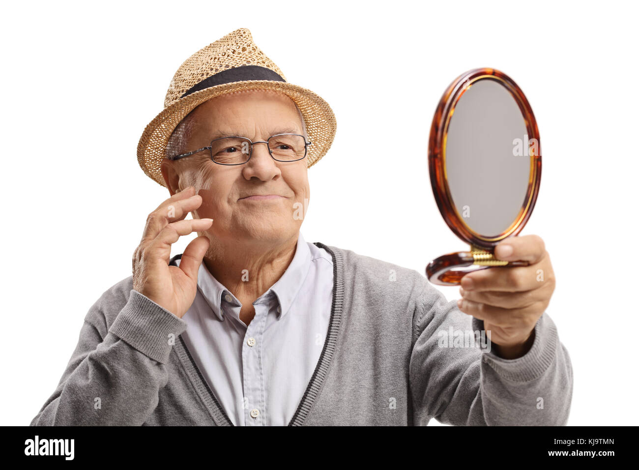 Elderly man looking at himself in a mirror and touching his face isolated on white background Stock Photo