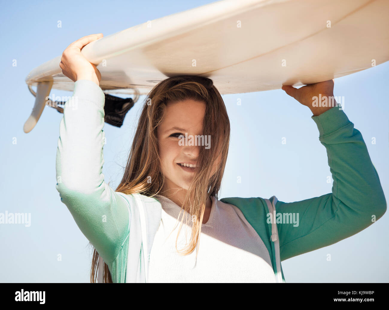 Teenage Girl In The Beach And Holding A Surfboard Over Her Head Stock