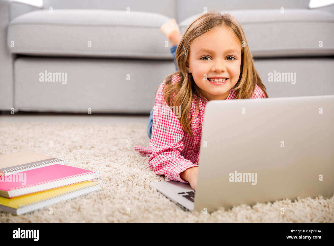 Happy little girl at home working with a laptop Stock Photo - Alamy