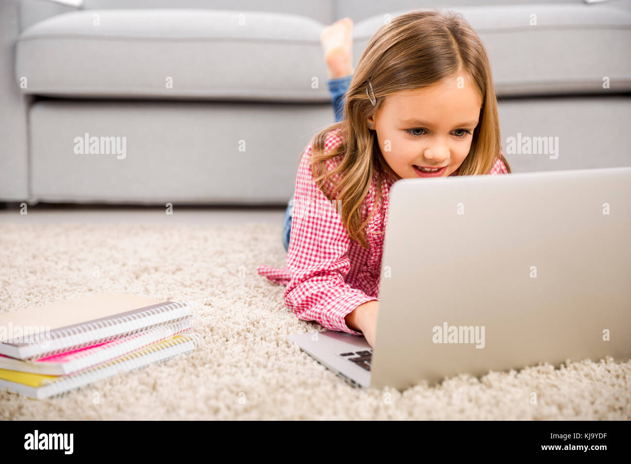 Happy little girl at home working with a laptop Stock Photo - Alamy
