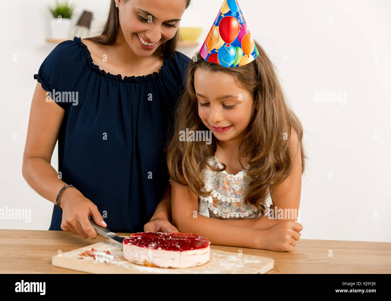 Shot of a mother and daughter cuting the cutting the birthday cake Stock Photo