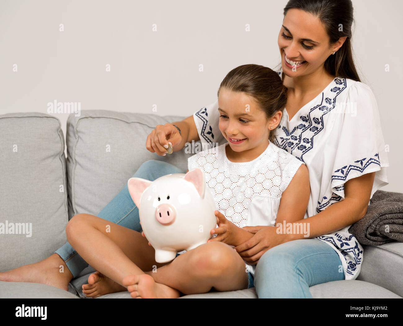 Mother and daughter putting coins into a piggy bank Stock Photo - Alamy
