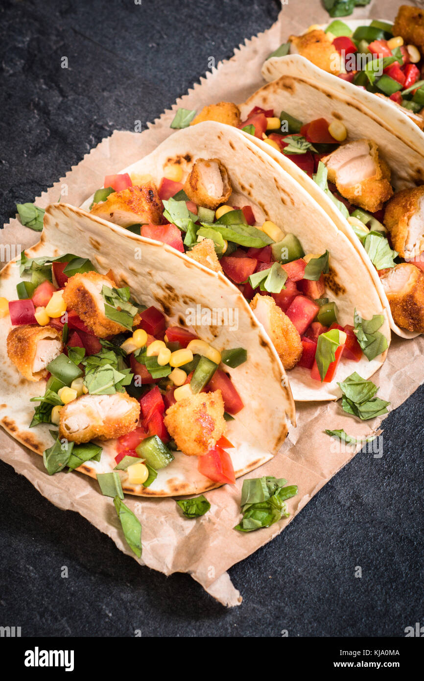 Tortilla sandwiches with fried chicken and vegetables on dark
