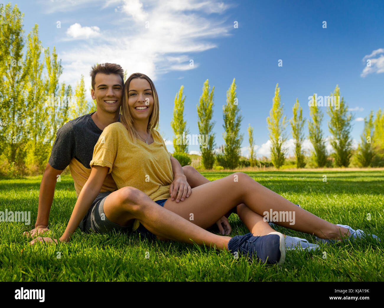 Young couple sitting on the grass and relaxing Stock Photo - Alamy