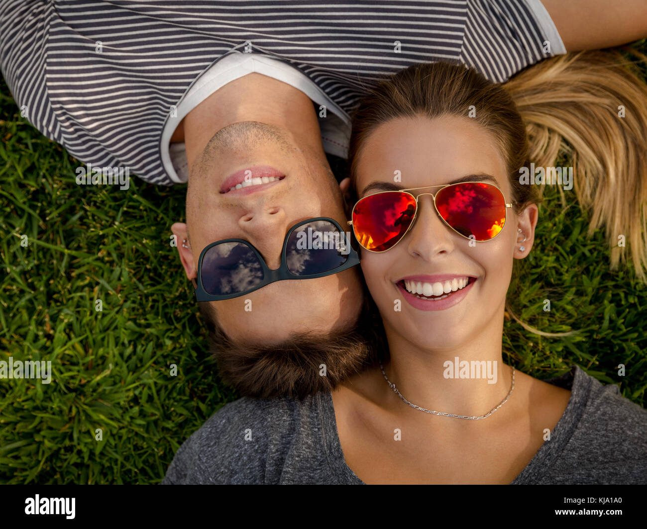 Portrait of a young beautiful couple lying on the grass Stock Photo - Alamy