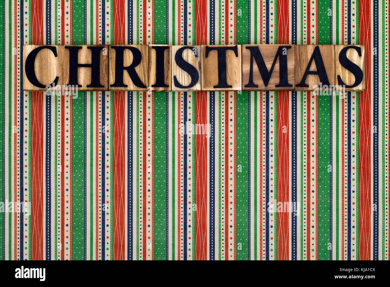 The word Christmas made from wooden block letters on a colourful striped background. Stock Photo