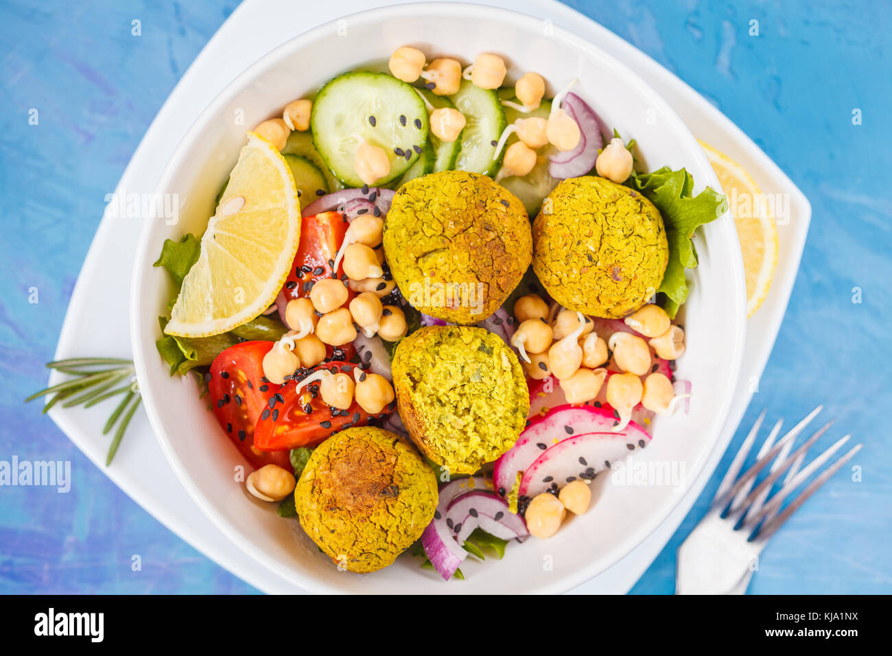 Baked falafel salad with vegetables and sprouted chickpeas, blue background. Vegan Healthy Food Concept. Stock Photo