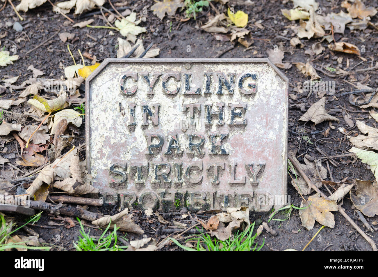 Old silver painted metal sign in the ground stating 'Cycling in the park strictly prohibited' in Grosvenor Park, Chester, UK Stock Photo