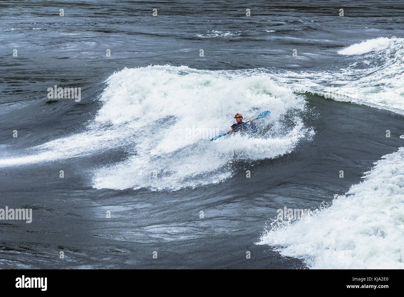 A playboater and his kayak almost disappear amid the foam of a huge wave at Sechelt Rapids ('Skookumchuck'), one of the world's fastest tidal passes. Stock Photo