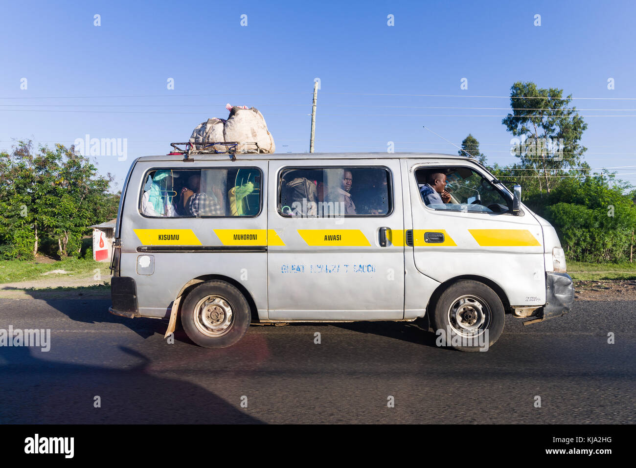 A small matatu minibus with passengers drives along a road, Kenya, East Africa Stock Photo