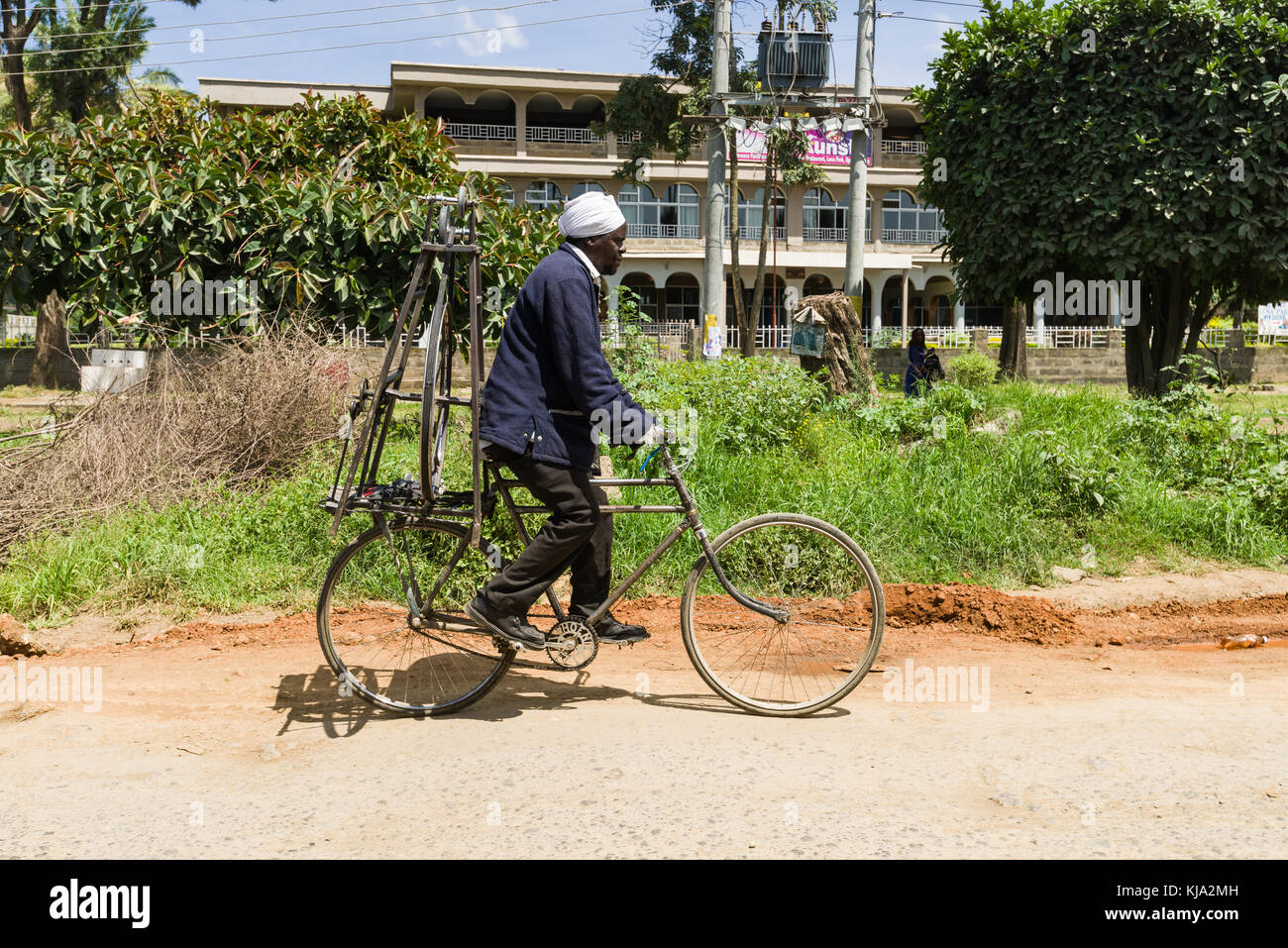 An African man riding on a bicycle with a knife sharpener on the back, Kenya, East Africa Stock Photo