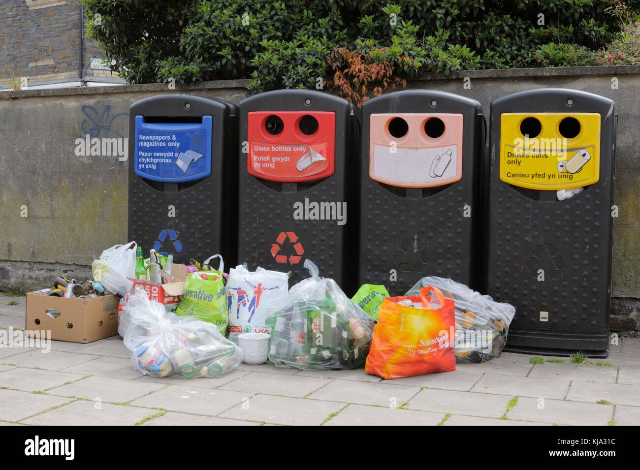 Colour coded waste recycling bins with piled excess glass waste, Wales