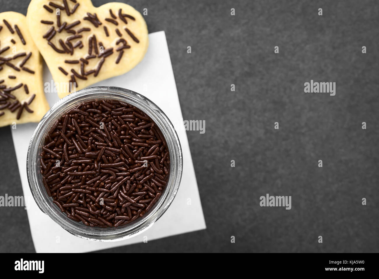 Chocolate sugar sprinkles in glass jar, photographed overhead on slate (Selective Focus, Focus on the sprinkles in the jar) Stock Photo