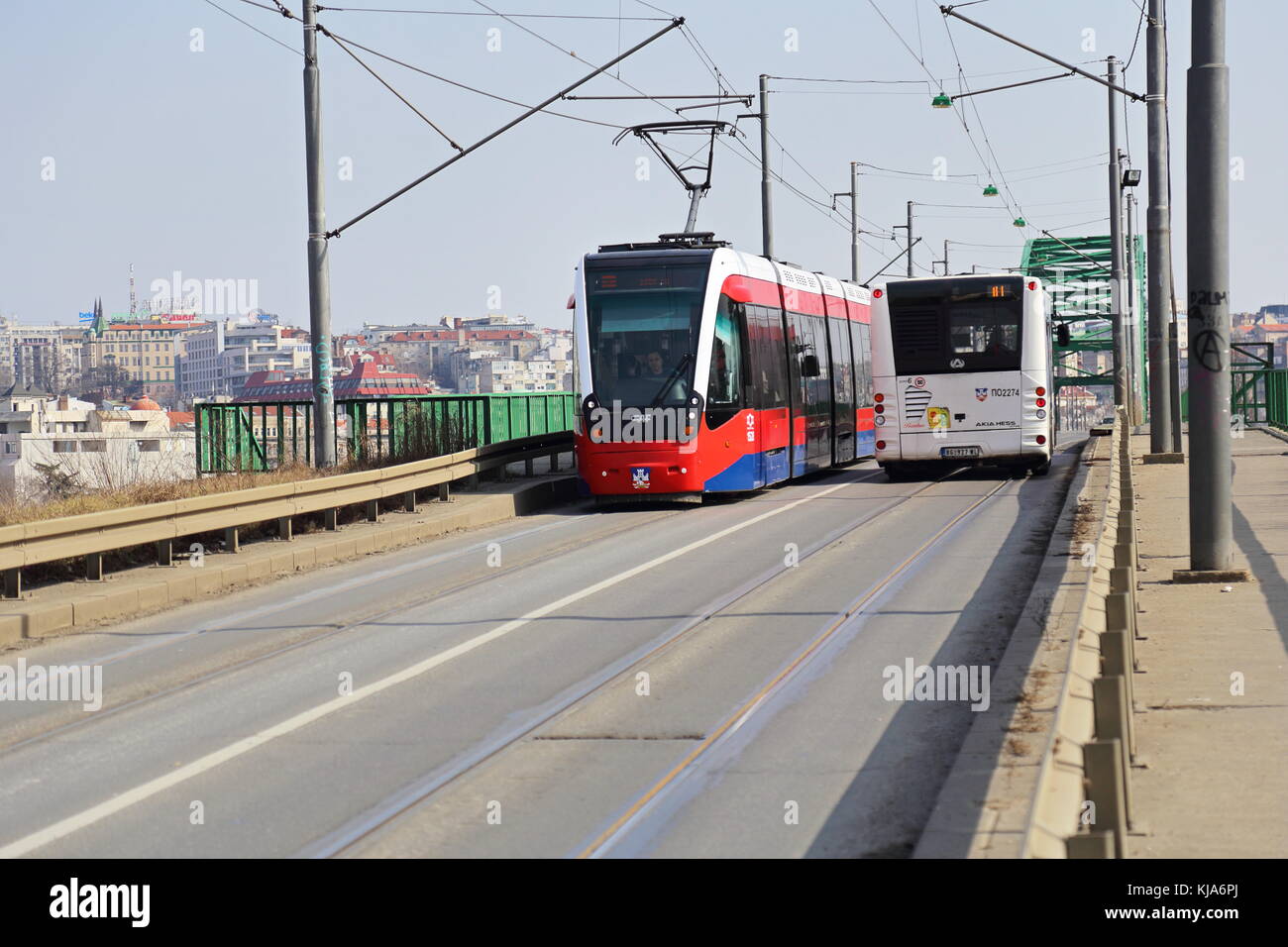 New red CAF Urbos 3 tram and white bus on Old Sava Bridge (tram bridge) in Belgrade, Serbia Stock Photo