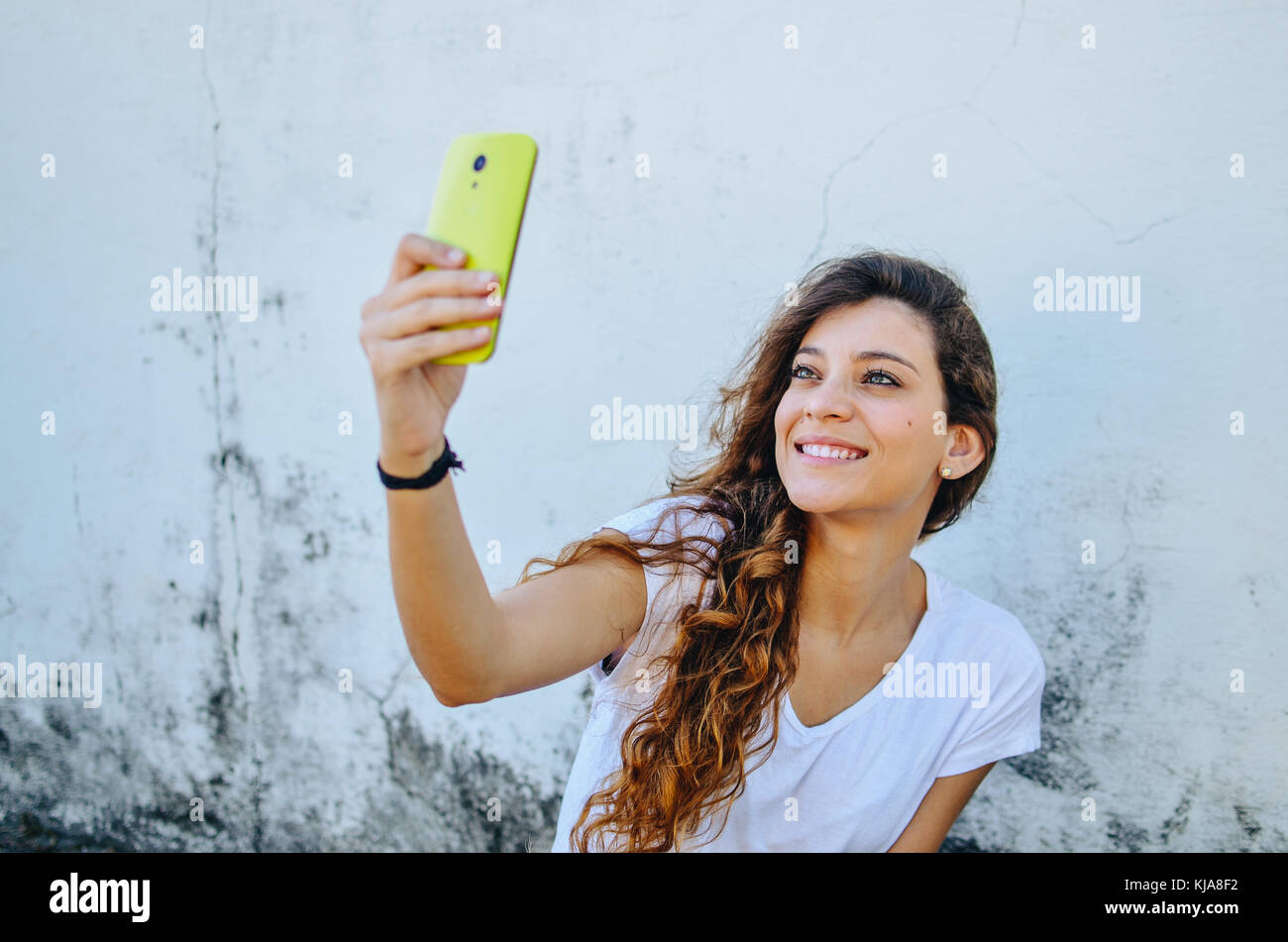 Young beautiful woman, holding her smartphone, take a selfie portrait ...