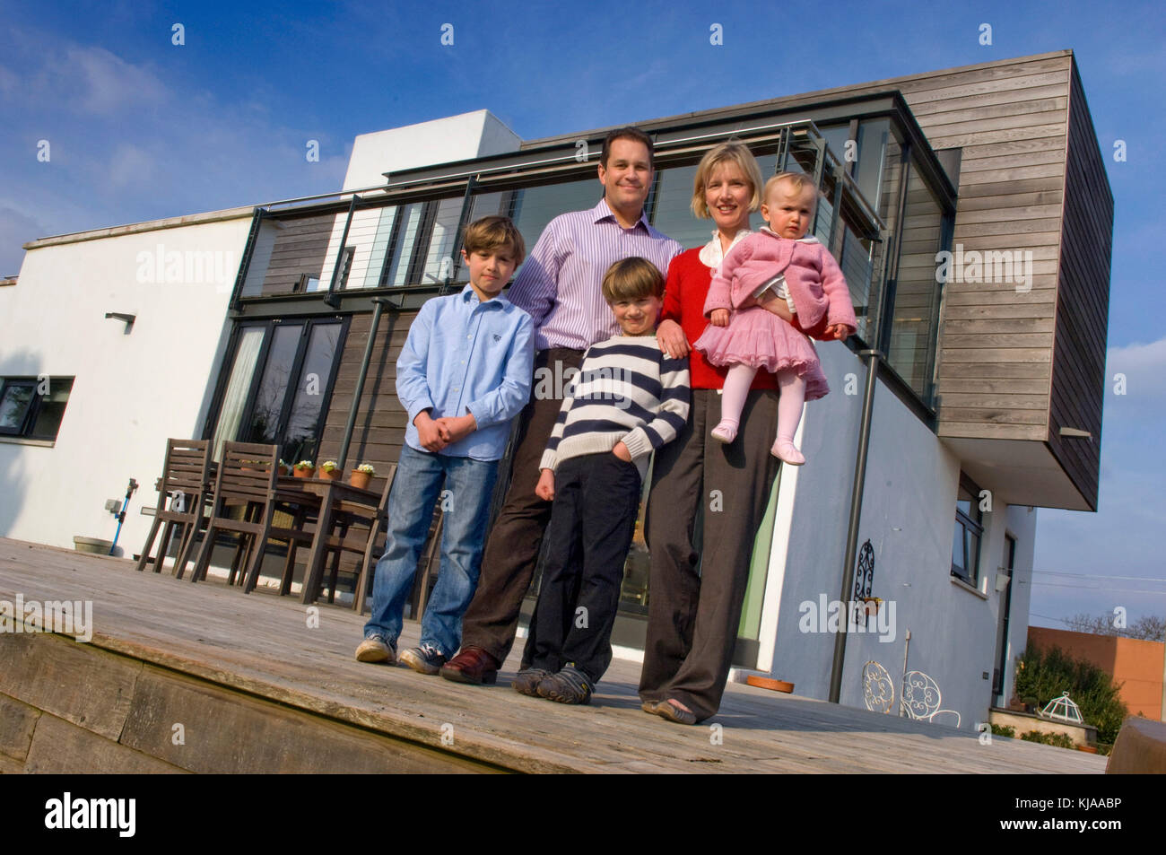 Family standing front of their home Stock Photo - Alamy