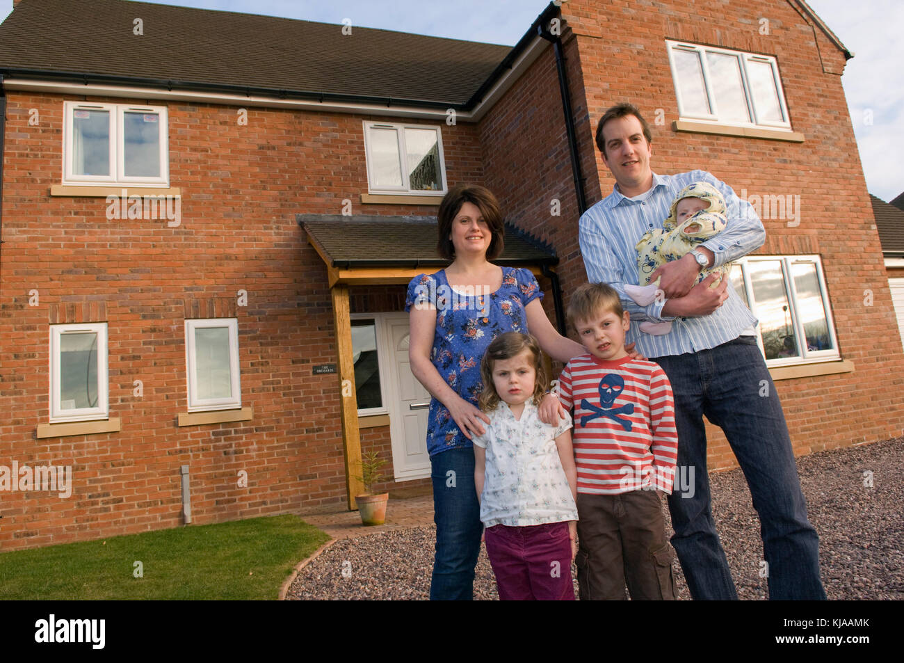 Family standing front of their home Stock Photo - Alamy