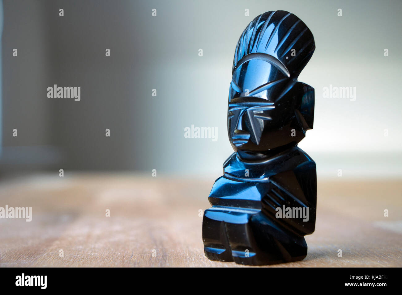 An aztec obsidian ancient statuette on wooden table in sunlight. Stock Photo