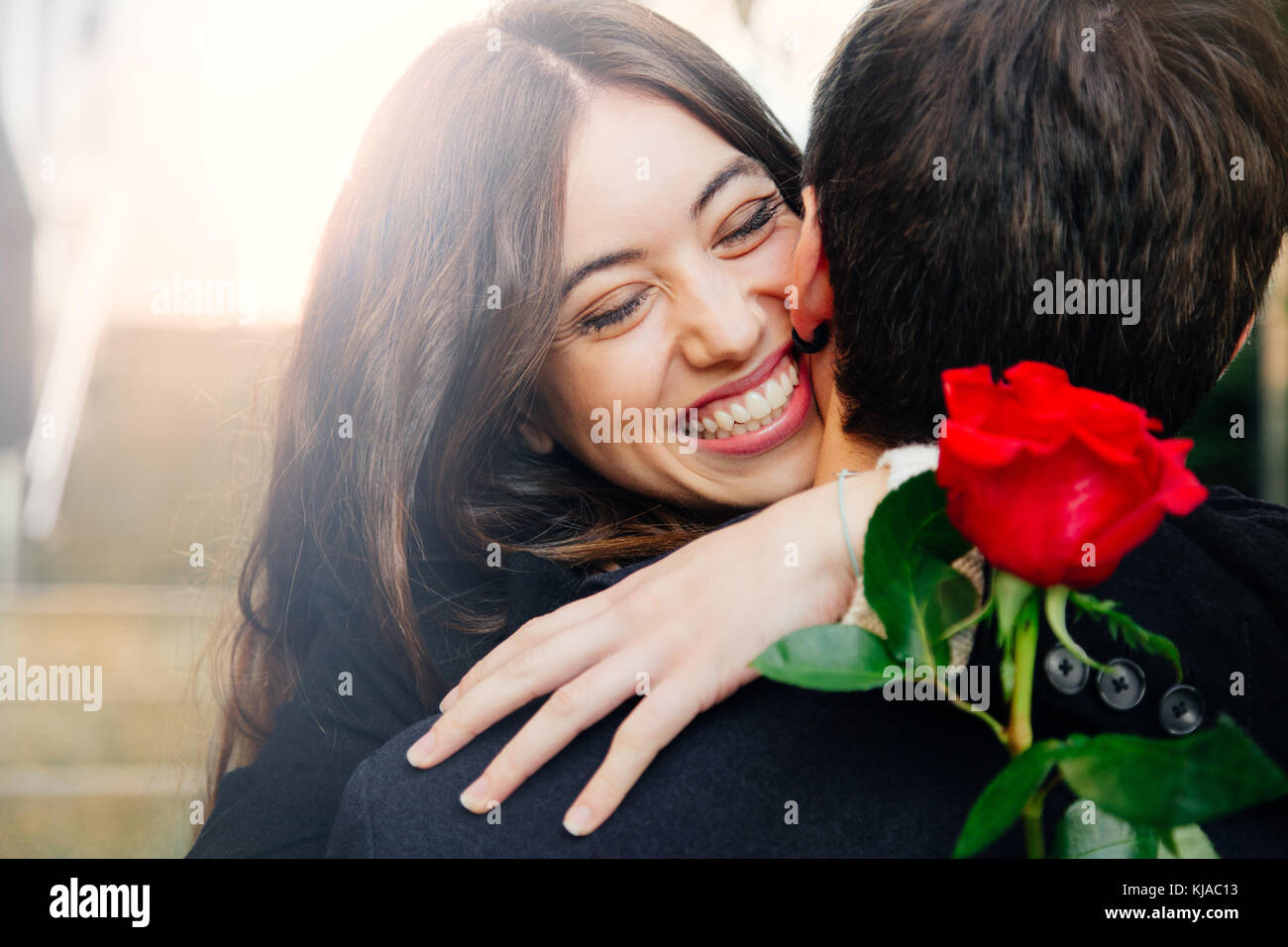 Beautiful and happy young woman in love hugging her boyfriend holding a ...
