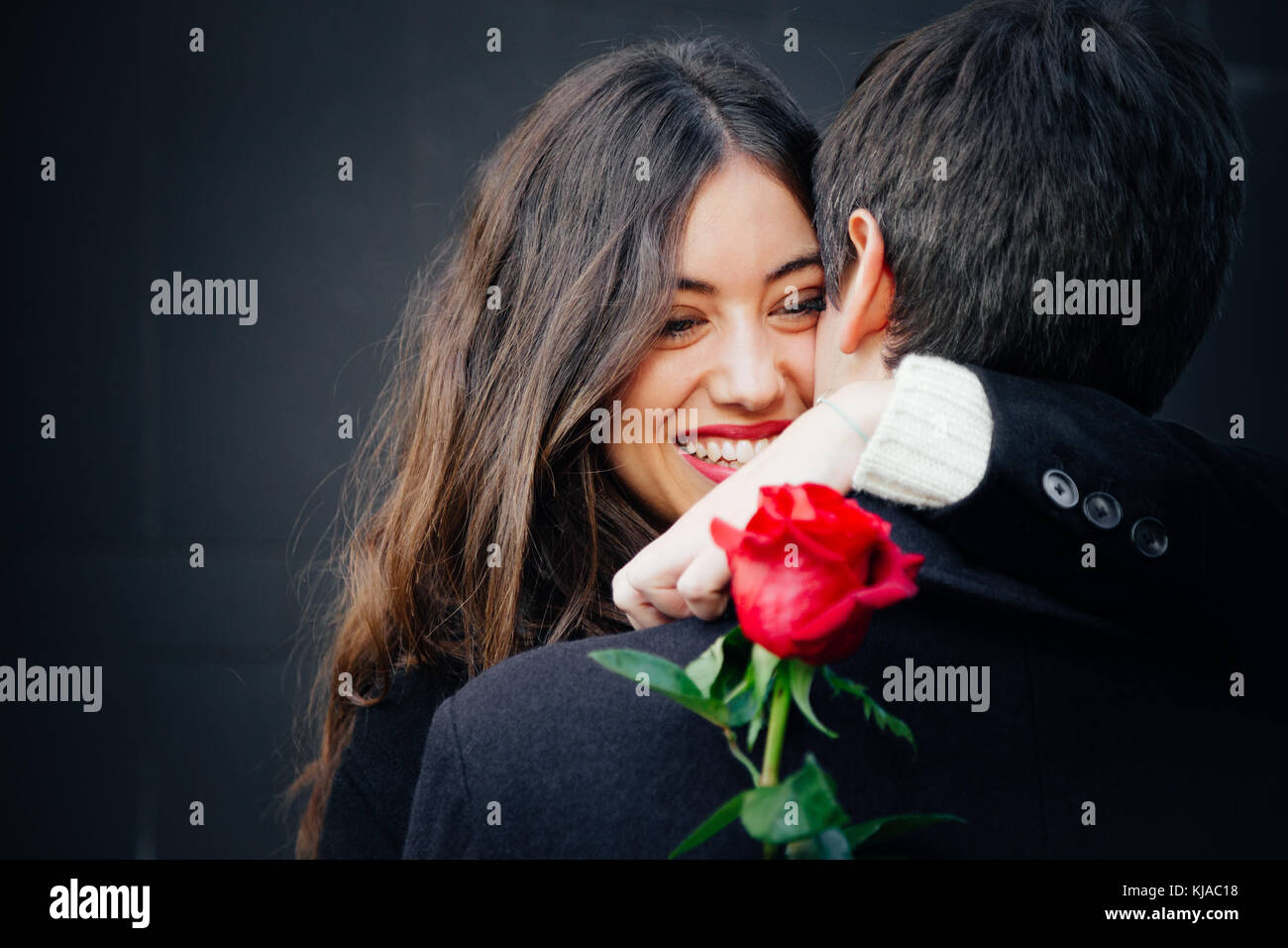 Beautiful and happy young woman in love hugging her boyfriend holding a ...