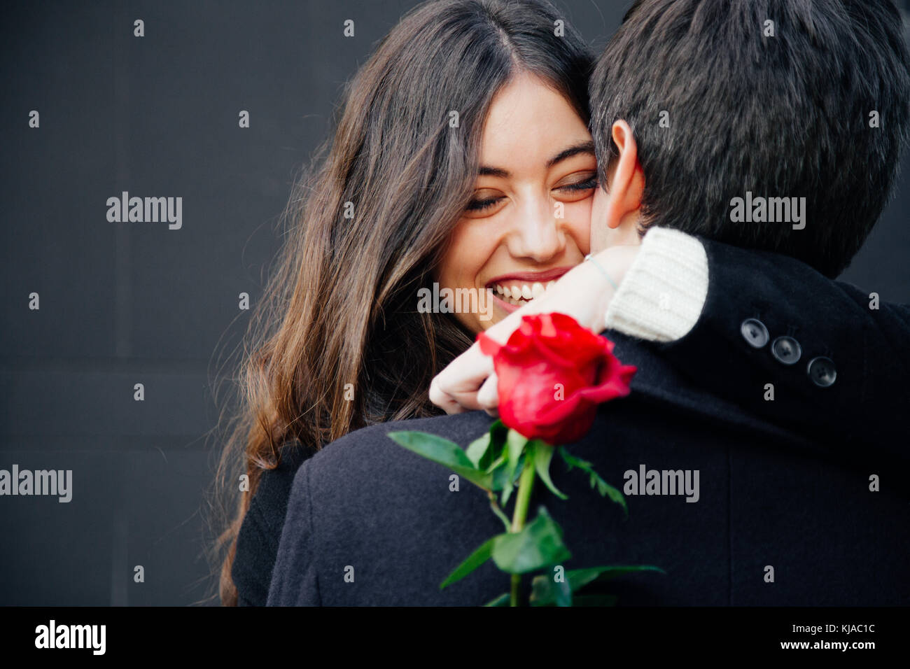 Beautiful and happy young woman in love hugging her boyfriend holding a ...