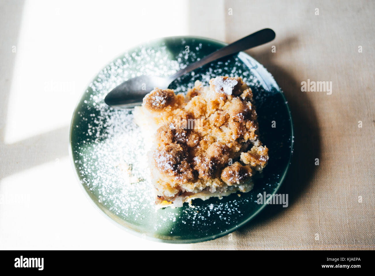 Apple crumble cake on a green plate on a wooden table Stock Photo
